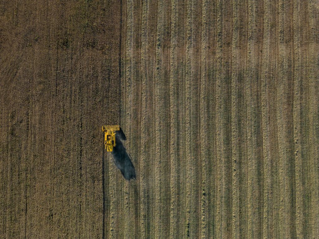 Drone shot of a combine harvester working on a vast agricultural field in Valladolid, Spain.